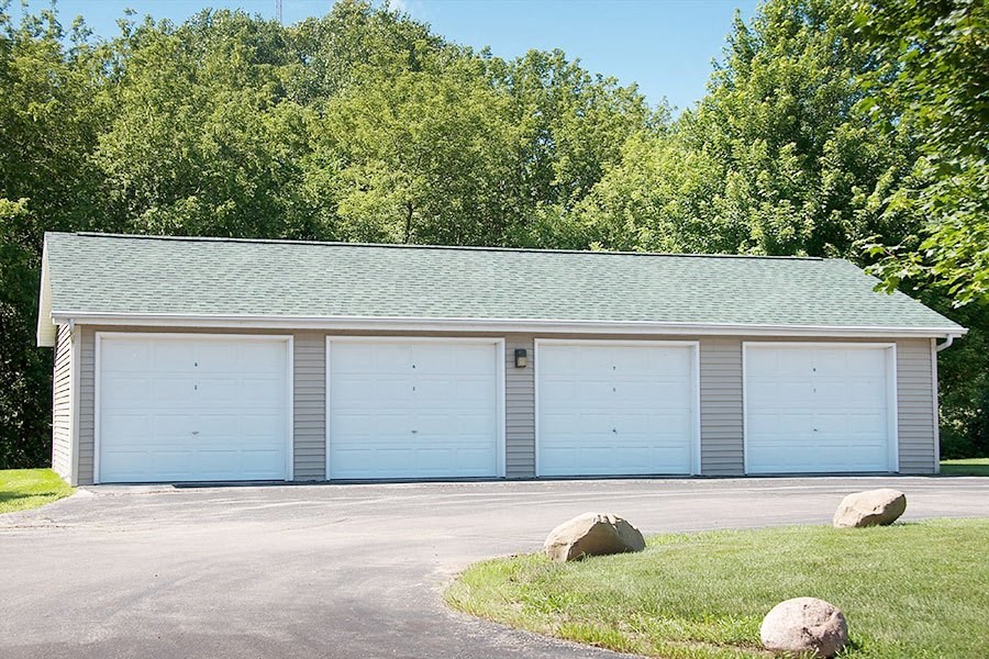 a white garage with blue doors and a green roof