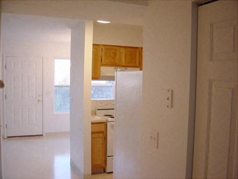 an empty kitchen with a refrigerator and a door