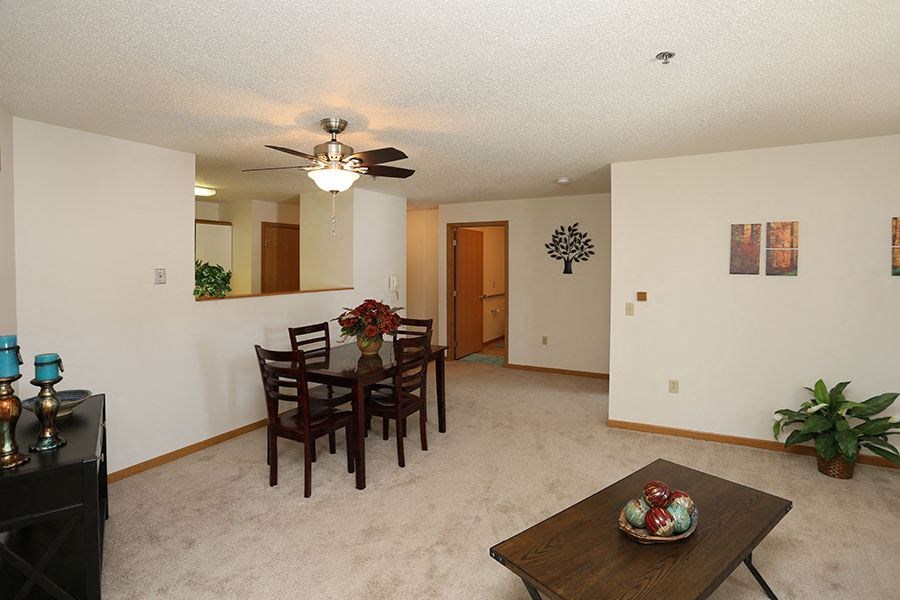 a living room and dining room with a table and a ceiling fan