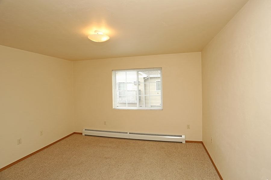 an empty living room with a window and carpet