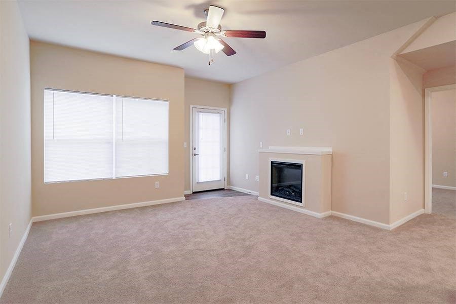 an empty living room with a fireplace and a ceiling fan