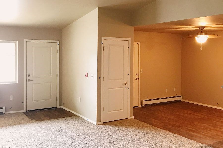 an empty living room with two doors and a ceiling fan