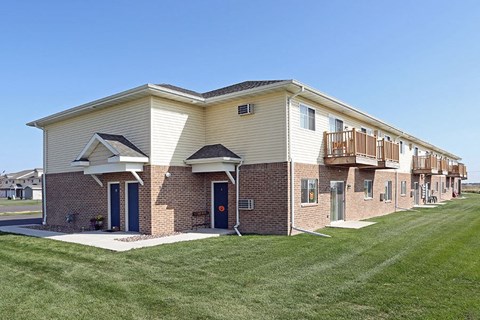 a brick building with a porch and a lawn
