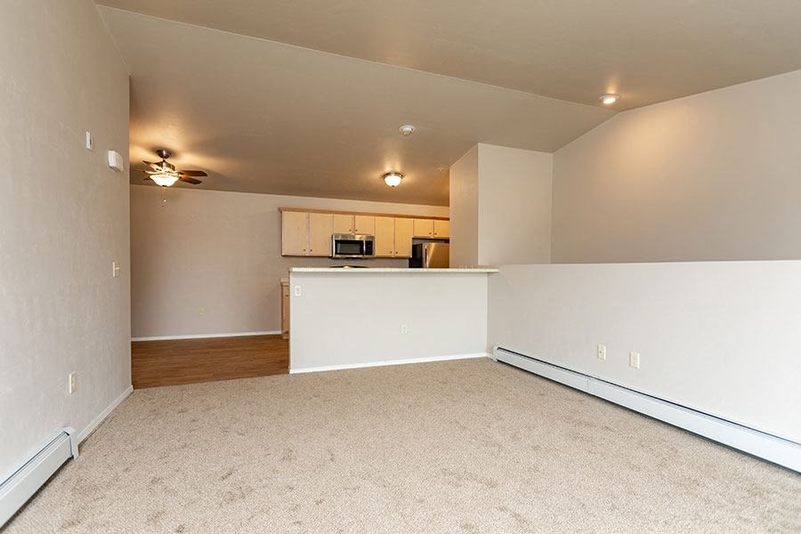 an empty living room with a kitchen in it