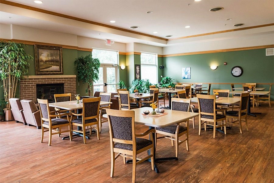 A restaurant with wooden tables and chairs and a fireplace.