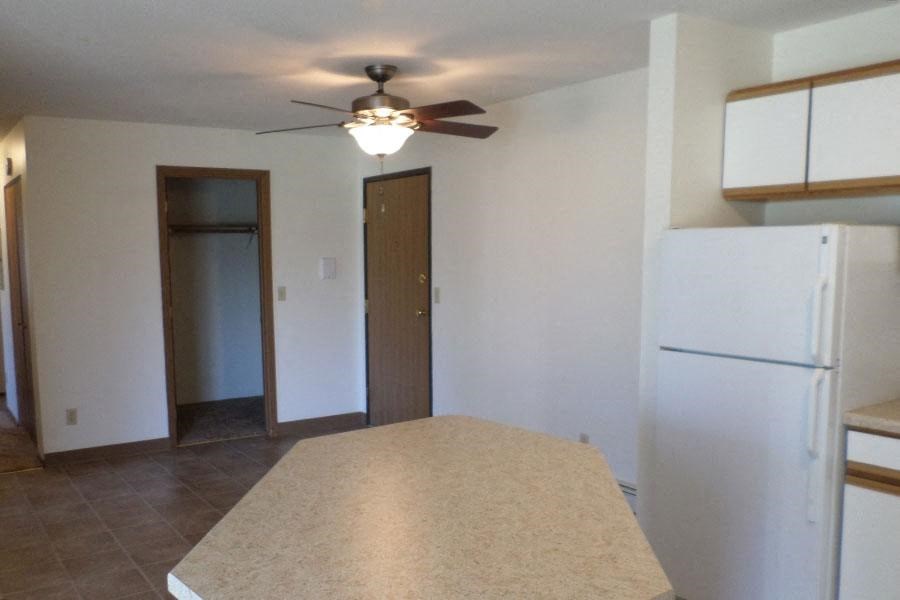 an empty kitchen with a ceiling fan and a refrigerator