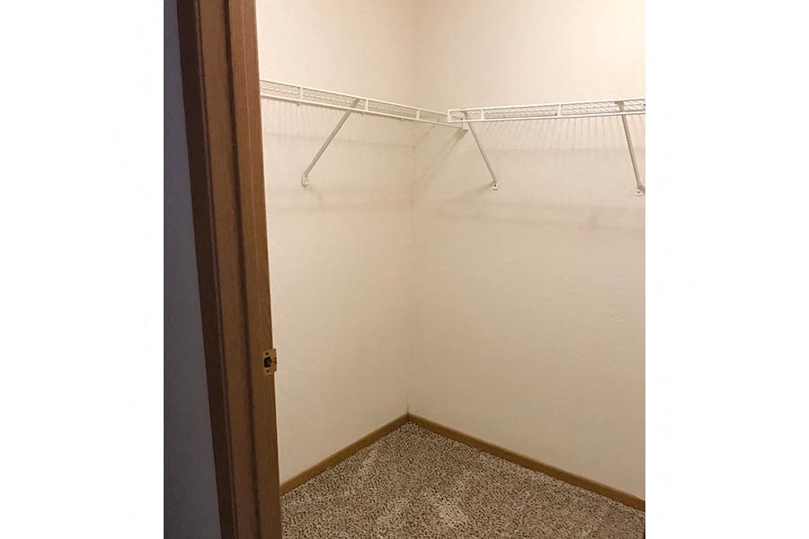 Empty room with a white wall and a carpeted floor.