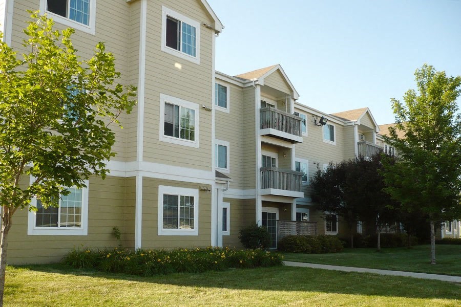 an apartment building with a grass yard and trees