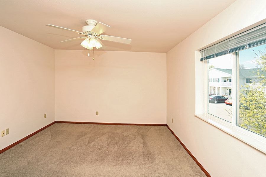 an empty living room with a ceiling fan and a large window