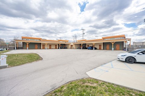A white car is parked in front of a building with orange trim.