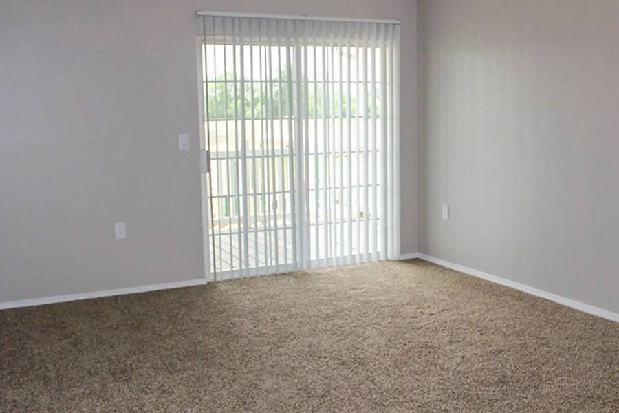 A room with a carpeted floor and a sliding glass door.