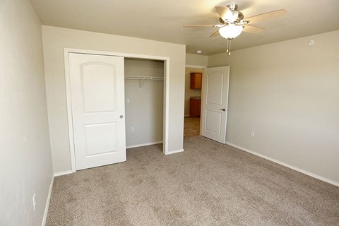 an empty bedroom with a closet and a ceiling fan