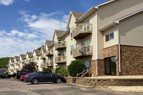 A car is parked in front of a building with a stone wall.