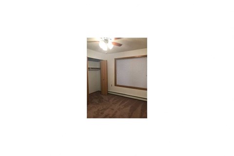 an empty living room with a window and a ceiling fan