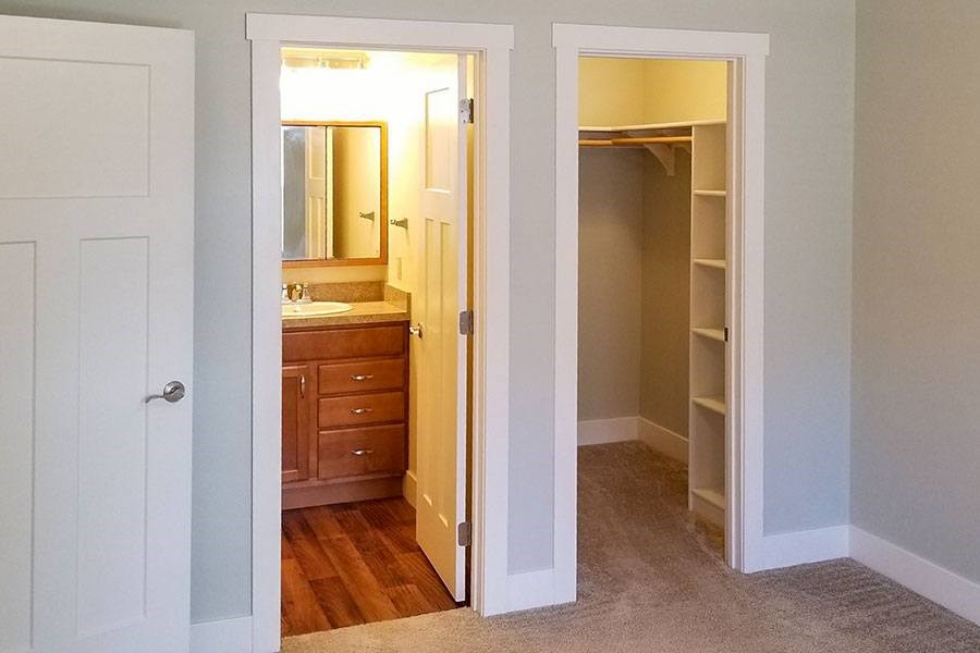 A white door is open to a room with a wooden dresser and mirror.