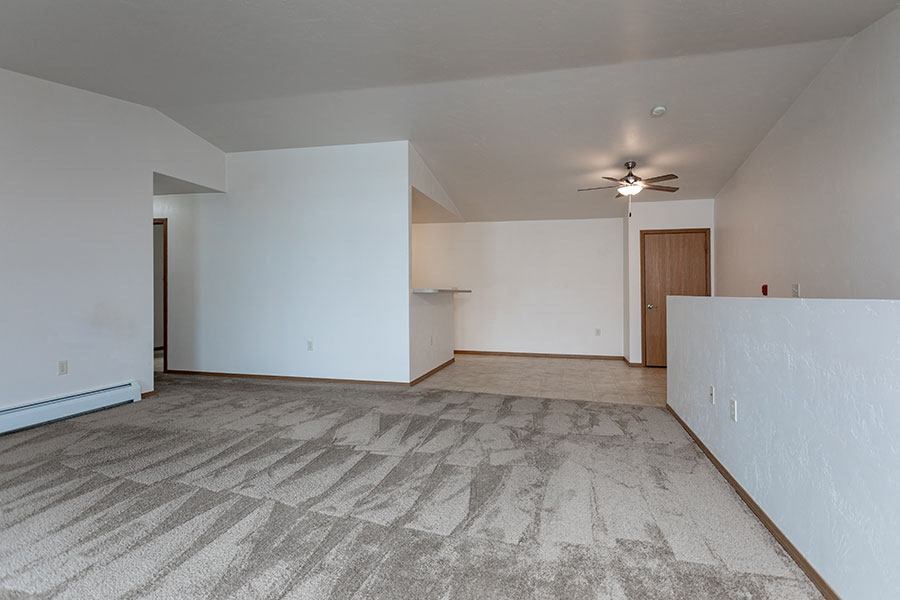 an empty living room with white walls and a ceiling fan