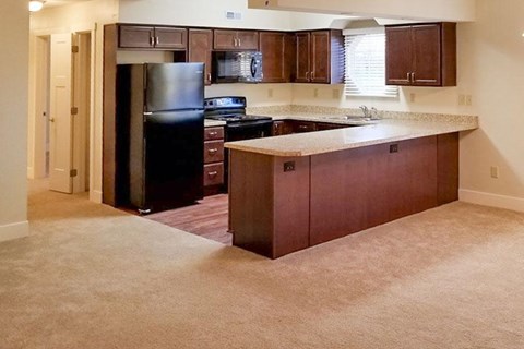 A kitchen with dark wood cabinets and a black refrigerator.