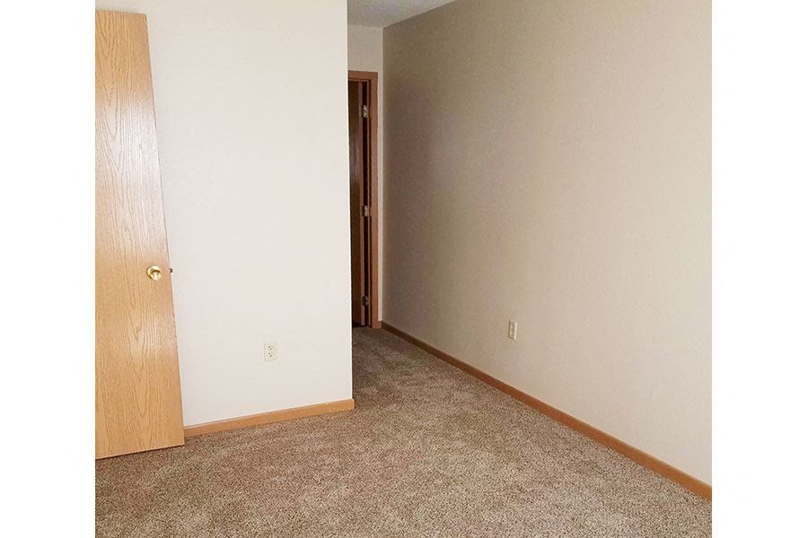 A room with a carpeted floor and a wooden door.