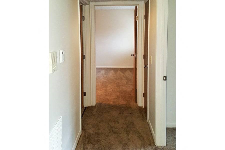 A hallway with a carpeted floor and a white door.