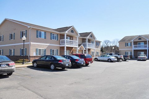 A parking lot with cars and apartment buildings in the background.