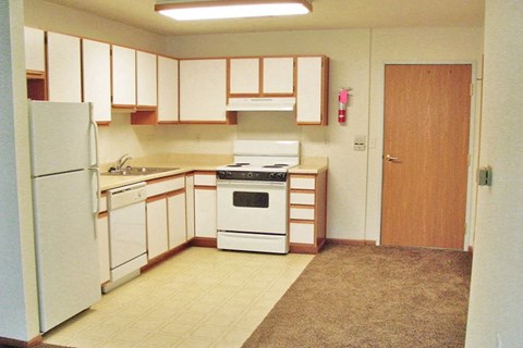 A kitchen with white appliances and wooden cabinets.