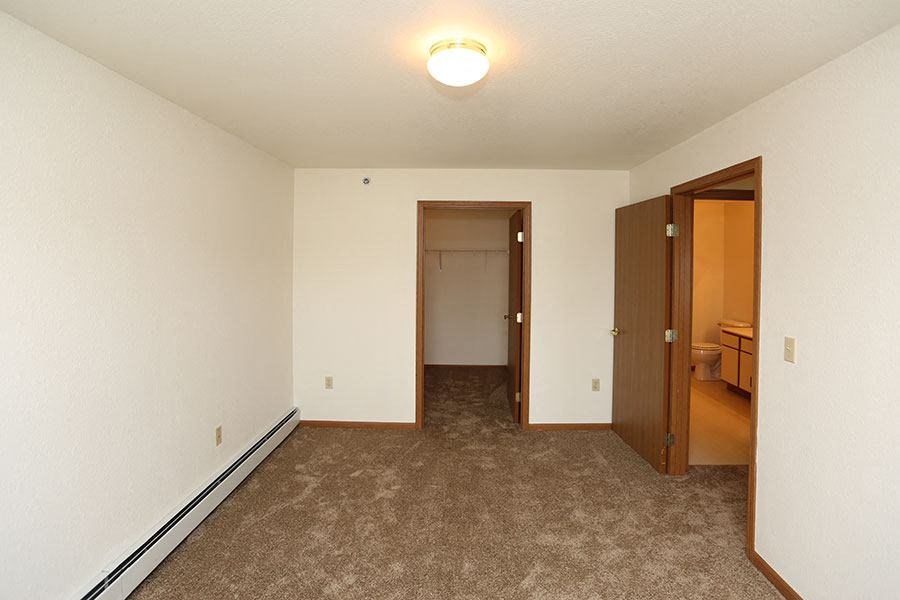 an empty living room with a door to a bedroom