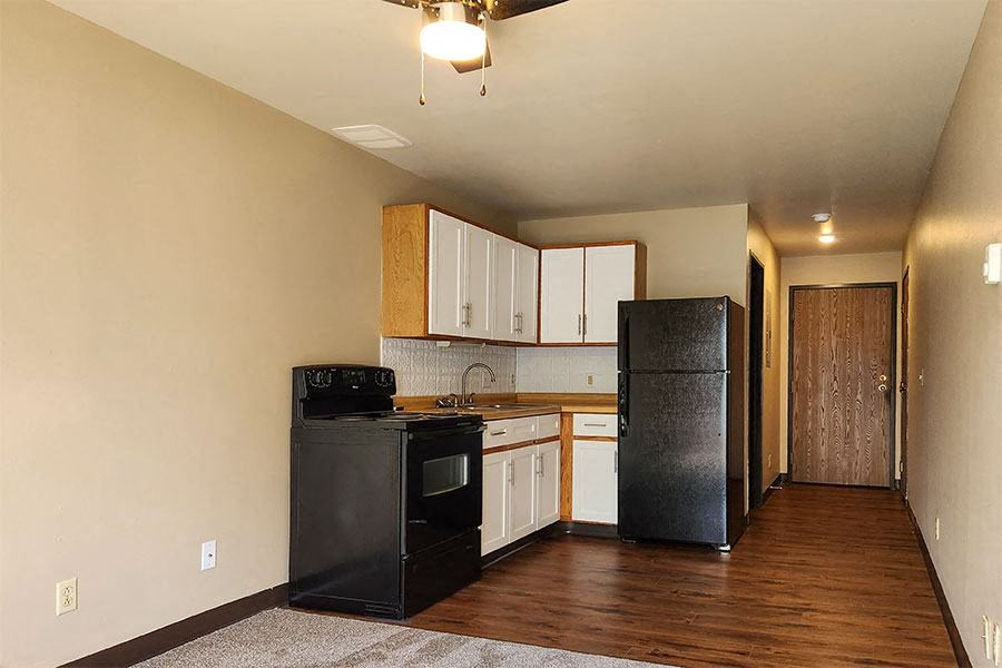 A kitchen with black appliances and wooden floors.