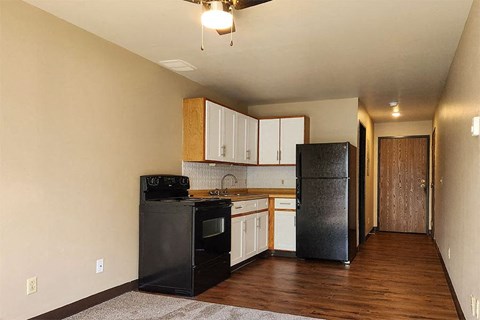 A kitchen with black appliances and wooden floors.