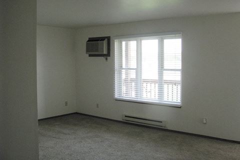 an empty living room with a window and a air conditioner