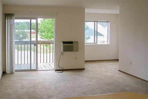 an empty living room with a heater and a balcony