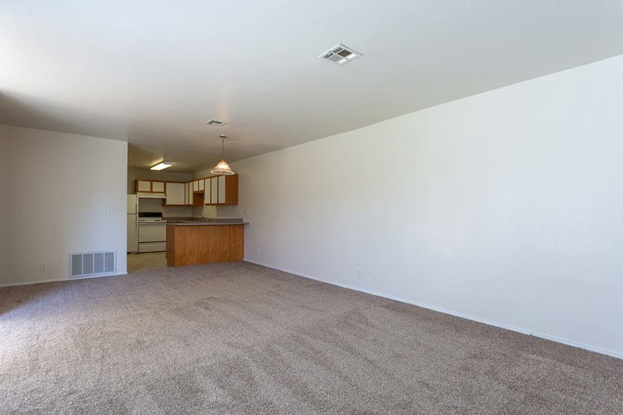an empty living room with a kitchen in it
