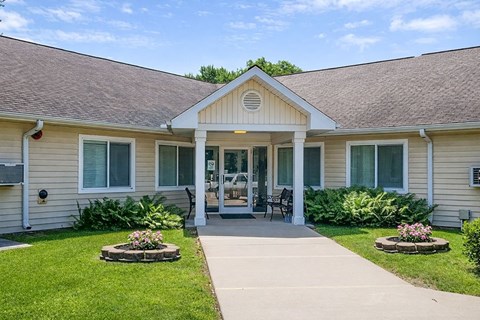 A small building with a front porch and a flower bed in front.