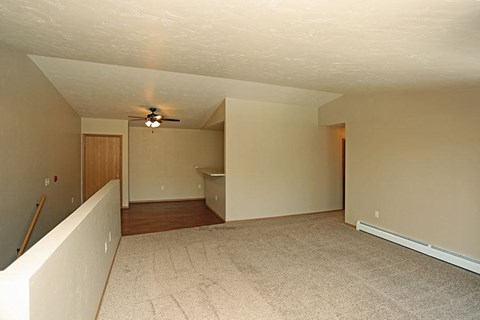 an empty living room with a ceiling fan