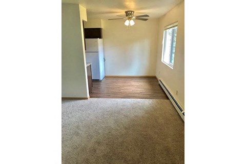 an empty living room with a ceiling fan and a kitchen