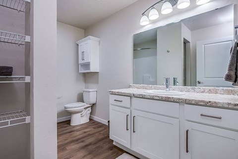 A bathroom with a toilet, sink, and cabinets.