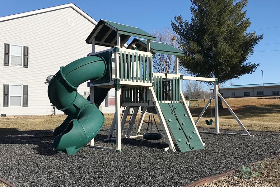 A green and white playground slide in front of a house.