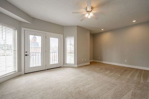A room with a carpeted floor and a ceiling fan.