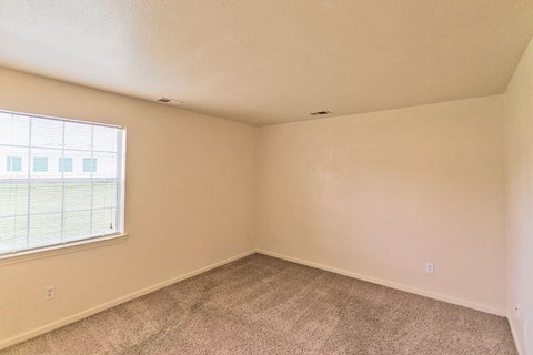an empty bedroom with a large window and carpet
