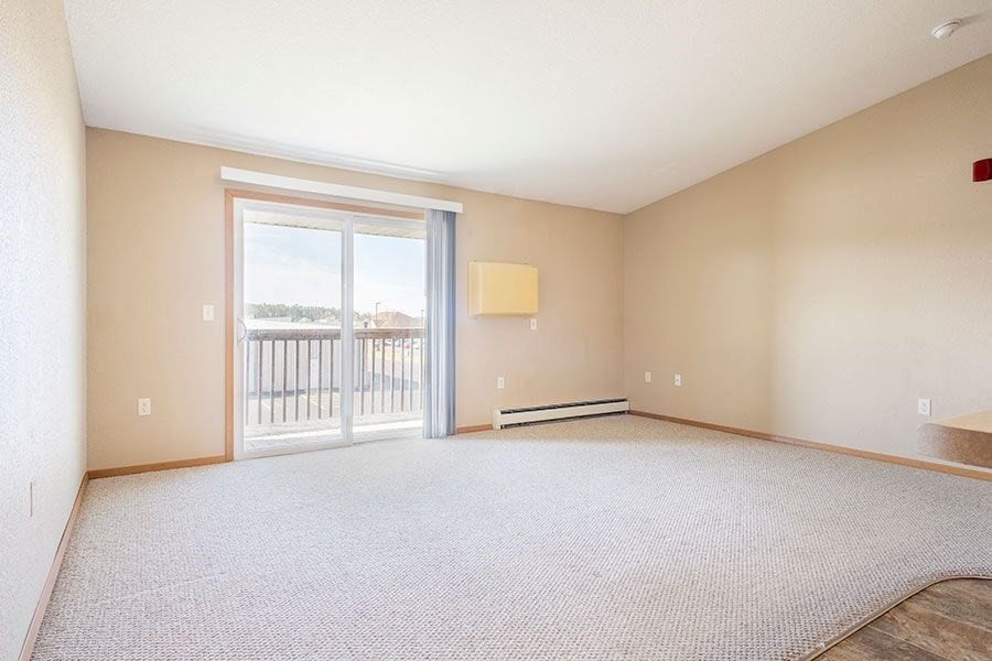 an empty living room with a sliding glass door to a balcony