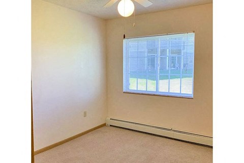 an empty room with a window and a ceiling fan