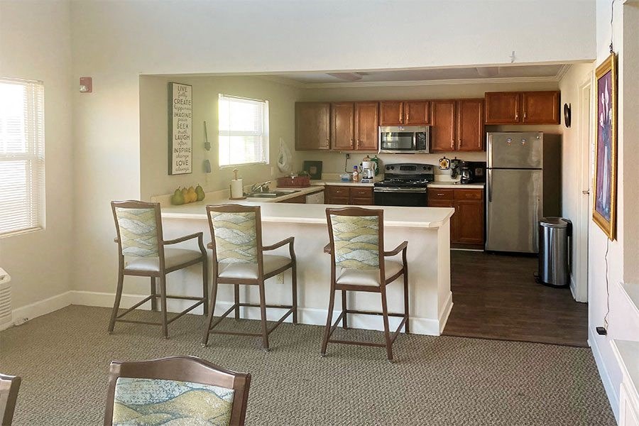 a kitchen with a bar with three chairs