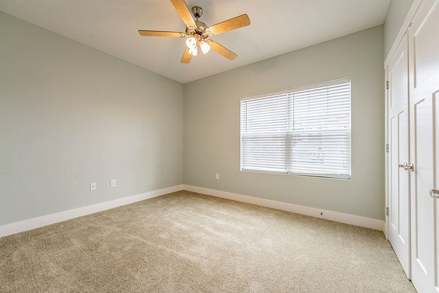A room with a ceiling fan and carpeted floor.