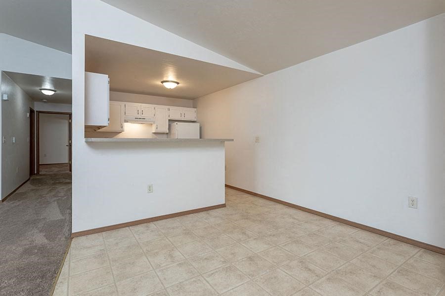 an empty living room and kitchen with a counter