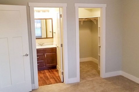 A white door opens to a bathroom with a sink and mirror.