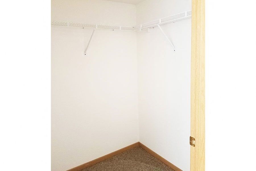 A white wall with a brown carpet and a white door.