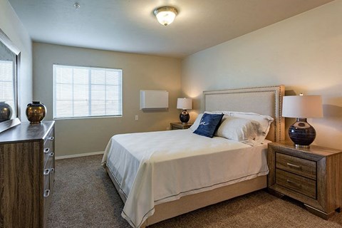 A bedroom with a bed, nightstand, and two lamps.