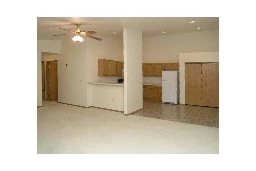 A kitchen with a refrigerator, cabinets, and a ceiling fan.