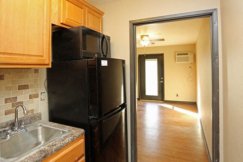 A black refrigerator in a kitchen with wooden cabinets.
