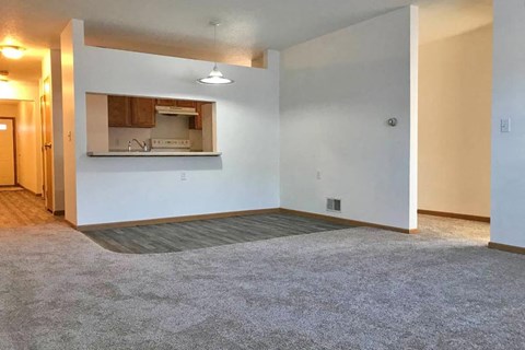 an empty living room with a kitchen in it