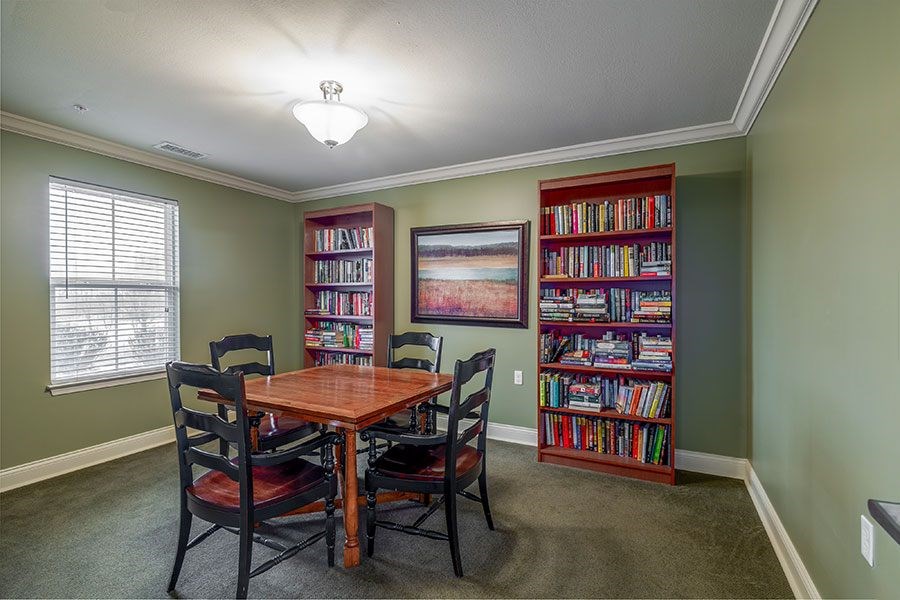 A room with a table, chairs and a bookshelf.